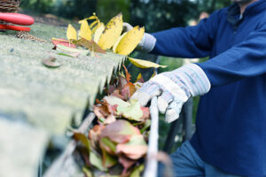 Gutter cleaning South Brunswick being perfomed by homeowner in blue shirt wearing light blue work gloves