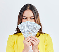 Woman holding a fan of cash from her Seaside Park rentals in front of her face